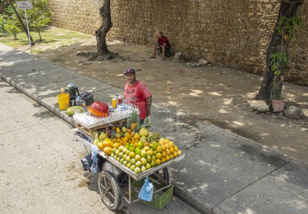 Téléchargez les photos : Carthagène, Colombie - 25 juillet 2023 : Vendeur de fruits et boissons ambulants qui poussent le chariot le long des remparts de la vieille ville. - en image libre de droit
