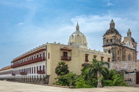 Cartagena, Kolumbien - 25. Juli 2023: Santuario de San Pedro Claver Kirchtürme, historische Fassade mit Kreuzgang und Museumsgebäuden nebeneinander unter blauer Wolkenlandschaft. Grünes Laub davor