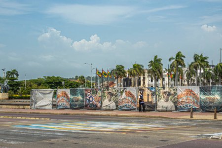 Téléchargez les photos : Carthagène, Colombie - 25 juillet 2023 : Sur l'Avenida Blaz de Lezo, clôture avec images corporelles, société de promotion touristique. L'autre côté est le plus ancien quai de la ville sous un paysage nuageux bleu - en image libre de droit