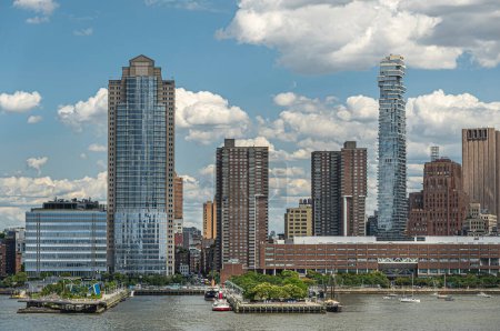 New York, NY, USA - 1. August 2023: City Headquarters Building und 56 Leonard Street Wolkenkratzer vom Hudson River aus unter blauer Wolkendecke. Blick geradeaus in die N. Moore Street. Grüne Baumgrenze, Pfeiler 25 und 26