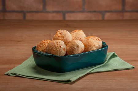 Cheese breads in a serving dish on wooden table.