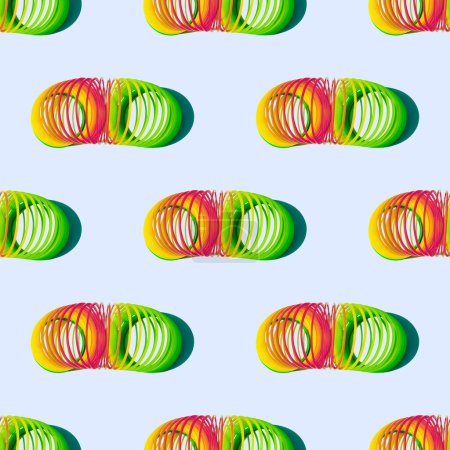 Photo for Flexible rainbow children's retro toy with shadows on a pale blue background. Seamless pattern. Slinky. Anti-stress toy - Royalty Free Image