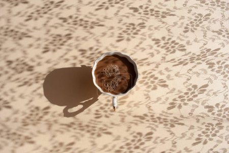 Photo for Shadows from openwork tulle falls on the table with a white cup of coffee with milk. Aesthetic flat lay, top view still life lifestyle concept. Abstract view with shadow and light - Royalty Free Image