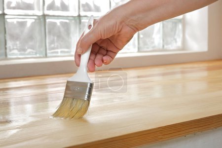 Foto de Varnishing of pine wooden plank floor or stairs, workers hand and paint  brush tool - Imagen libre de derechos
