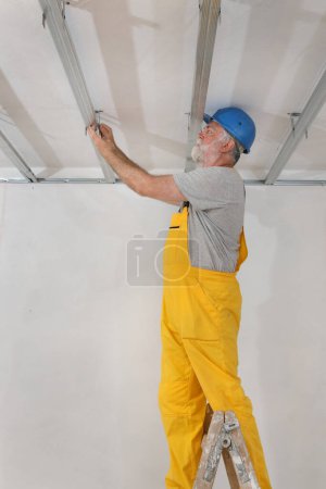 Foto de Trabajador colocación de perfil de aluminio para techo de yeso y aislamiento - Imagen libre de derechos
