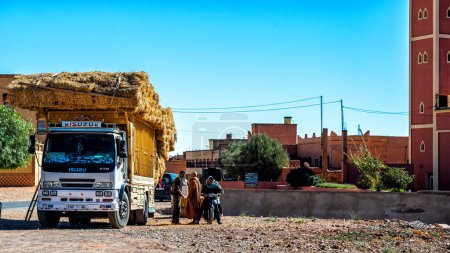 Téléchargez les photos : Tinghir, Draa-Tafilalet, Maroc - 27 novembre 2022 : Un marchand de foin itinérant vendant sa marchandise dans un marché de rue. - en image libre de droit