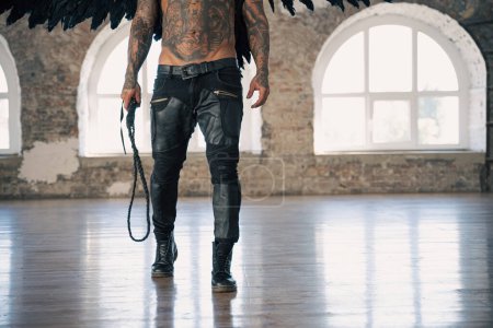man with wings going to punish us with his whip.  angel with whip. hot man with wings and tattoo 