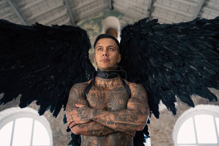 Foto de Man portrait. Close up portrait of handsome male angel. Guy with tattoo. hot man in leather . man with collar and whip. Angle with dark wings - Imagen libre de derechos