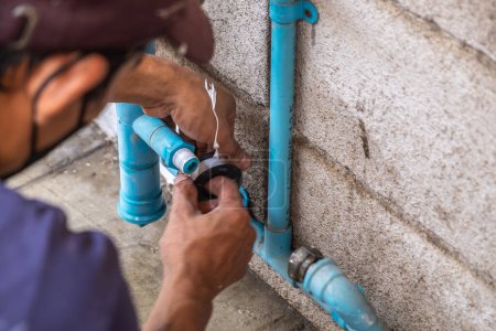 Téléchargez les photos : Un plombier mécanicien répare un robinet de conduite d'eau qui fuit près du compteur d'eau. - en image libre de droit