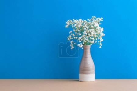 Téléchargez les photos : Petites fleurs blanches sur fond bleu. Décor doux pour la maison. Fleurs de Gypsophila. Fleurs blanches dans un vase. - en image libre de droit