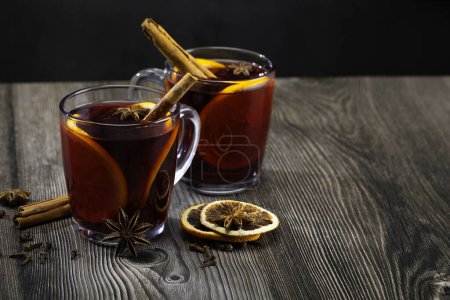 Photo for Glass of mulled wine with orange slice. Mulled wine and ingredients on a wooden table. Handheld shooting - Royalty Free Image