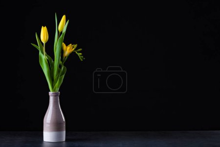 Foto de Un ramo de tulipanes amarillos en un jarrón en el suelo. - Imagen libre de derechos