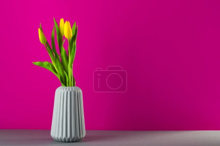 Foto de Ramo de tulipanes amarillos en un jarrón sobre fondo rosa, flores de primavera para las mujeres, espacio de copia - Imagen libre de derechos