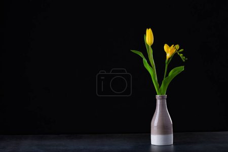 Foto de Un ramo de tulipanes amarillos en un jarrón en el suelo. - Imagen libre de derechos