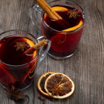 Glass of mulled wine with orange slice. Mulled wine and ingredients on a wooden table. Handheld shooting
