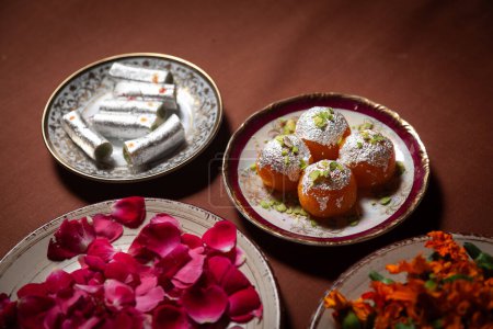 Rouleau de noix de cajou doux "Kaju Roll" et "Motichoor Ladoo" ou "Bundi Laddu" avec des pétales de fleurs. 