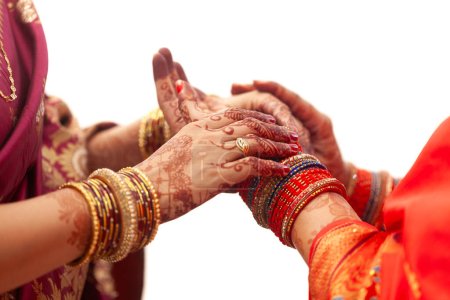 Téléchargez les photos : Deux femmes tatouées au henné ajustent leurs bracelets lors d'une célébration de mariage indienne. - en image libre de droit
