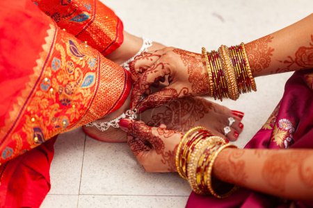Concepto de Ceremonia de Boda India. Una novia india recibe sus tobilleras de plata puestas por otra mujer.