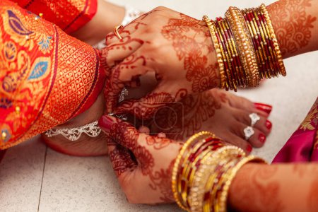 Concept de cérémonie de mariage indien. Une mariée indienne obtient ses bracelets de cheville en argent mis par une autre femme.