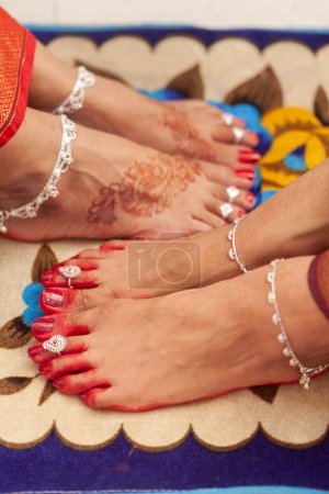 Indian Wedding Concept. Schöne Füße von zwei Frauen in einer indischen Hochzeit, dekoriert mit verheißungsvoller roter Farbe (Alta), Fußkettchen und Zehenringen.
