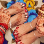 Indian Wedding Concept. Beautiful feet of two women in an Indian wedding, decorated with auspicious red color (Alta), anklets, and toe rings.
