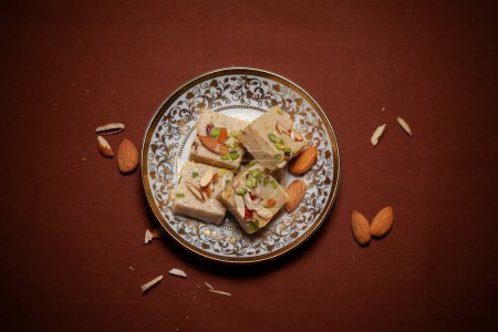 Top view  an Indian Traditional sweet called "Barfi", garnished with sweet almonds, served on a ceramic plate.