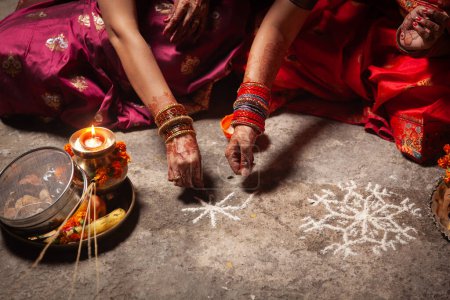Deux Indiennes créent un motif hindou (rangoli) propice au Festival Karwa Chauth.