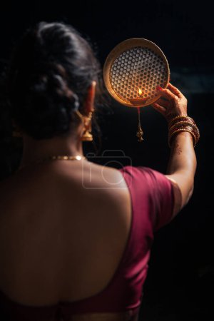 Une Indienne regardant la lune à travers un tamis pendant le festival Karwa Chauth.