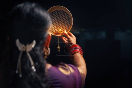 Foto de Una mujer india mirando a la luna a través de un tamiz durante el festival Karwa Chauth. - Imagen libre de derechos