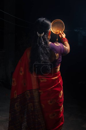 Eine Inderin blickt während des Karwa Chauth-Festes durch ein Sieb auf den Mond.