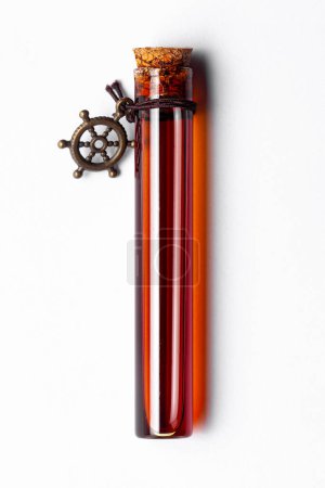 Top-down view of a glass vial containing dark amber color essential oil for cosmetics and natural medicine.