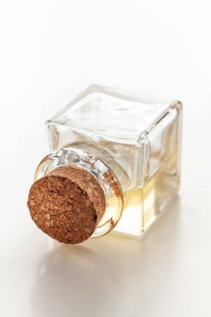 Eine quadratische Glasflasche, die hellgelbes ätherisches Öl für Kosmetika und natürliche Medizin enthält.
