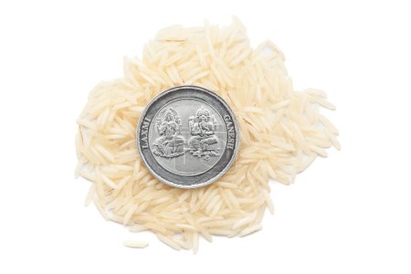 A Silver Coin engraved with Hindu deities Ganesha and Laxmi placed over rice (Oryza sativa), on a white background Top view.