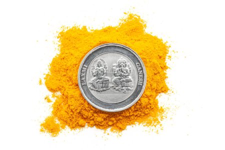 Top-down view of a Silver Coin engraved with Hindu deities "Ganesha and Laxmi" is placed over a Turmeric (Haldi) isolated on a white background.