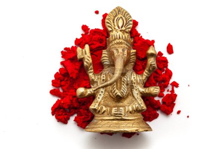 Das Messingidol des Hindugottes Ganesha steht isoliert über einer rot gefärbten Sindoor (Zinnoberrot) auf weißem Hintergrund. Ansicht von oben