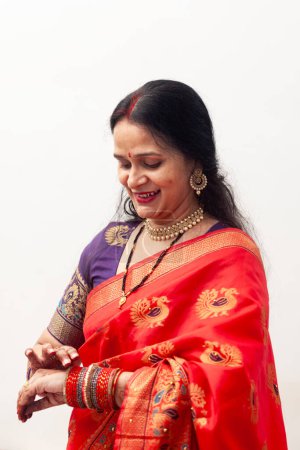 A joyful Indian woman is dressed in a colorful saree and adjusting her bangles.