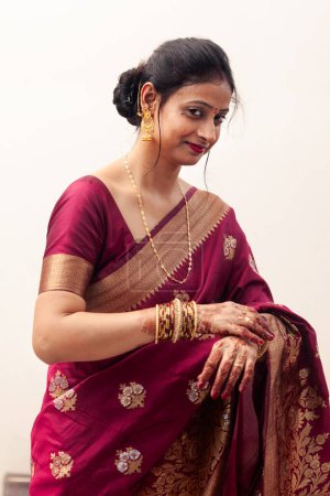 Eine schöne, glückliche Inderin trägt einen Sari und blickt direkt in die Kamera.