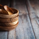 Stacked Wooden bowls, along with a wooden scoop on a wooden background.