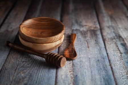 Foto de Cuencos de madera, junto con una cuchara de madera y un gotero de miel sobre un fondo de madera. - Imagen libre de derechos