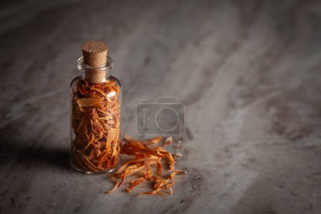 Photo for A small glass bottle filled with organic mace  (Myristica fragrans) or javitri is placed on a marble background. - Royalty Free Image