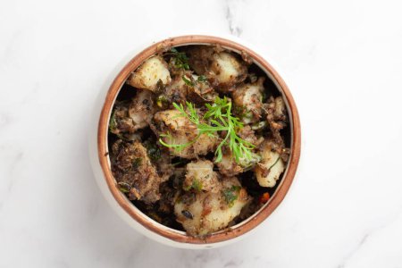 Makro-Nahaufnahme des indischen vegetarischen Klassikers Jeera Aloo - Kartoffeln mit Kreuzkümmel, garniert mit grünem Koriander, frischen Blättern und grünem Chili. 