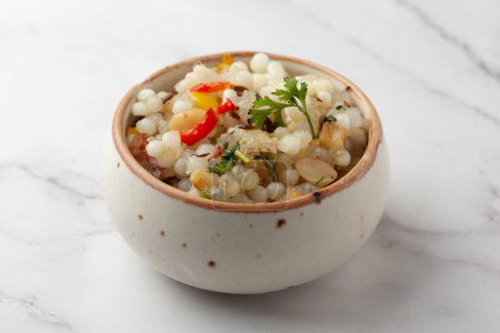 Photo for Close-up of Sabudana Khichadi - An authentic dish from Maharashtra made with sago seeds and garnished with coriander leaves served in ceramic bowl - Royalty Free Image