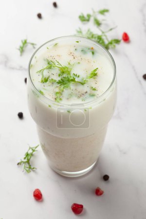 Großaufnahme des Sommergetränks Buttermilch oder Mattha oder Chhachh Glas garniert mit Koriander aus Milch und Quark. 