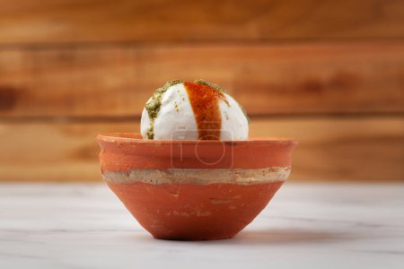 Chaat Dahi vada (AKA Dahi Bhalla, Doi Bora, mosaru vade, Dahi Bara, thayir vadai, perugu vada ). Prepared by soaking vadas in thick dahi (yogurt). Garnished with tamarind chutney sweet and  coriander spicy chutney