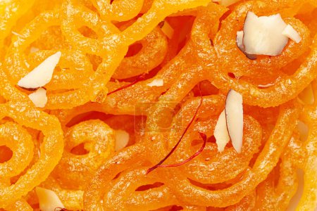 Close-Up of Indian Classical  Sweet Jalebi . Garnished with kesar (Saffron) and dry nuts, Jalebi is one of the most delicious sweets widely used in India. Selective Focus, Selective Focus on Subject, Background Blurred white .