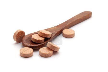 Concept de soins de santé. Une cuillère en bois remplie de pilules et de comprimés médicaux orange. Isolé sur fond blanc.