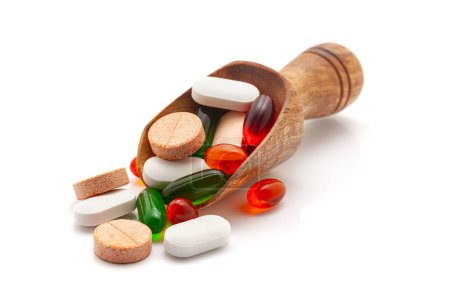 Concepto de salud. Una cucharada de madera llena de diferentes tabletas médicas, píldoras y cápsulas. Aislado sobre un fondo blanco.