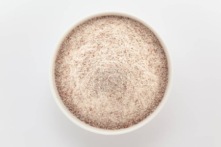 Ragi biologique (Eleusine coracana) ou farine de millet dans un bol en céramique blanche. Isolé sur un fond gris. Vue du dessus