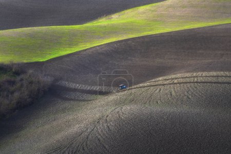 Téléchargez les photos : Tracteur labourant les champs en Toscane au coucher du soleil. Volterra, province de Pise. Italie - en image libre de droit