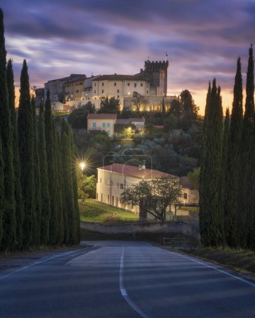 Téléchargez les photos : Château de Rosignano Marittimo et vue sur le village depuis une route de cyprès au coucher du soleil. Région Toscane, province de Livourne, Italie - en image libre de droit
